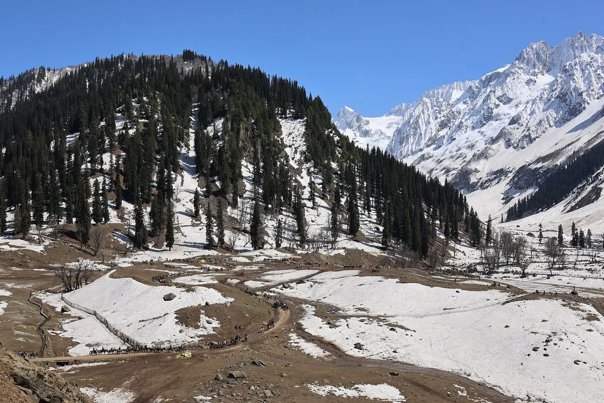 Snow on the ground and snow-capped peaks above pine forest in Sonamarg in April