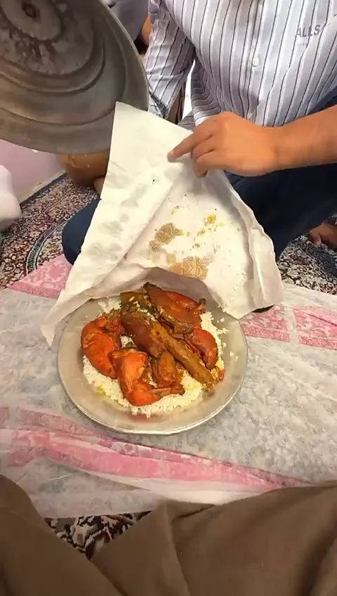 Lid lifted off a Wazwan trami to show fried ribs (Tabakh maaz) and kebabs on a bed of rice, served on the floor at a Kashmiri wedding