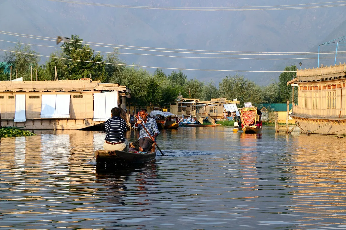 Shikara being paddled on Dal Lake in Srinagar past houseboats in the evening light