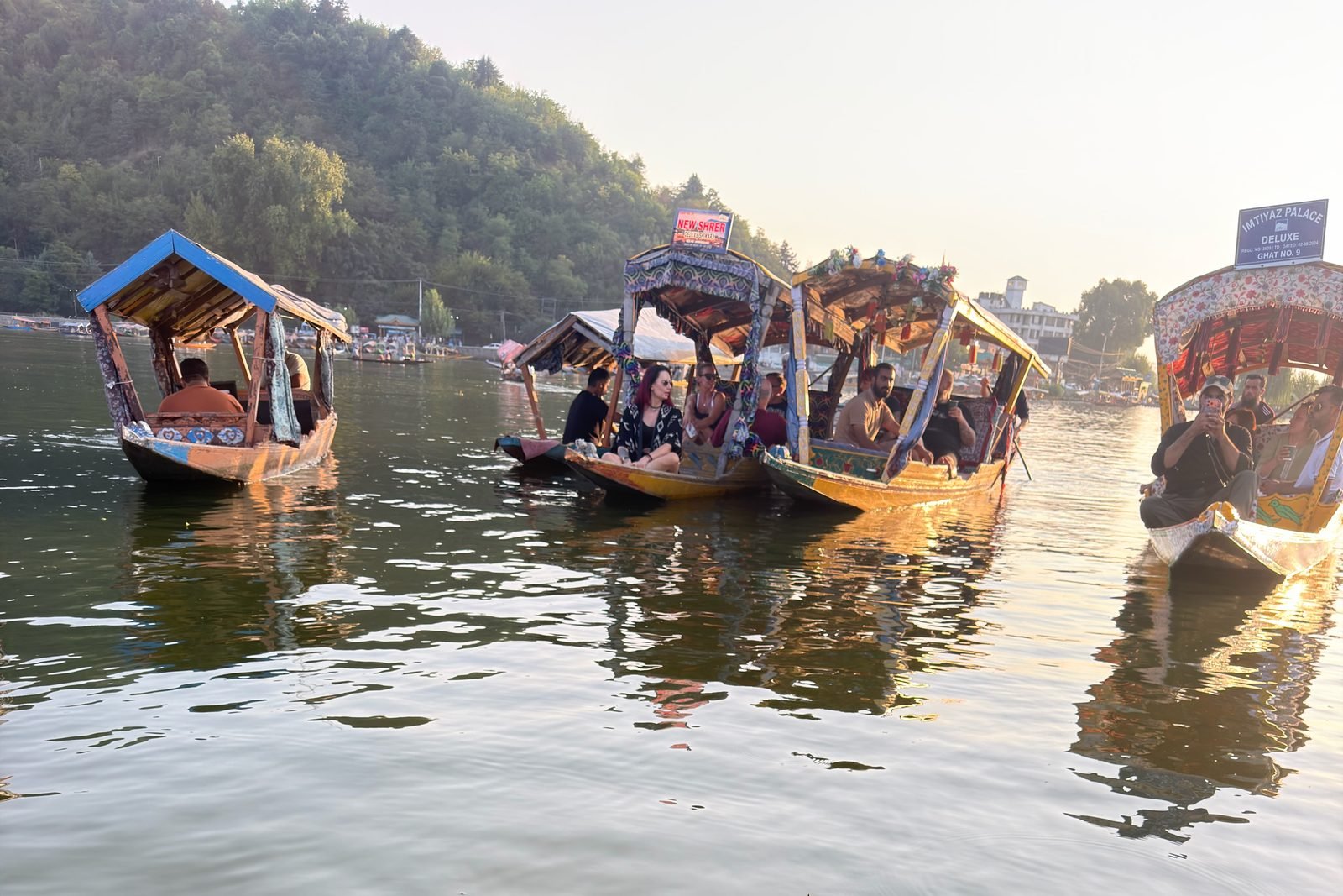 Decorated shikaras with tourists on Dal Lake in Srinagar at golden hour, with wooded hills behind