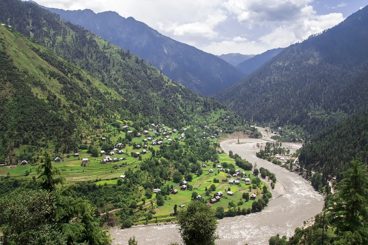 Keran village on terraced green fields above the Kishanganga river, with the valley and mountains stretching away on both banks