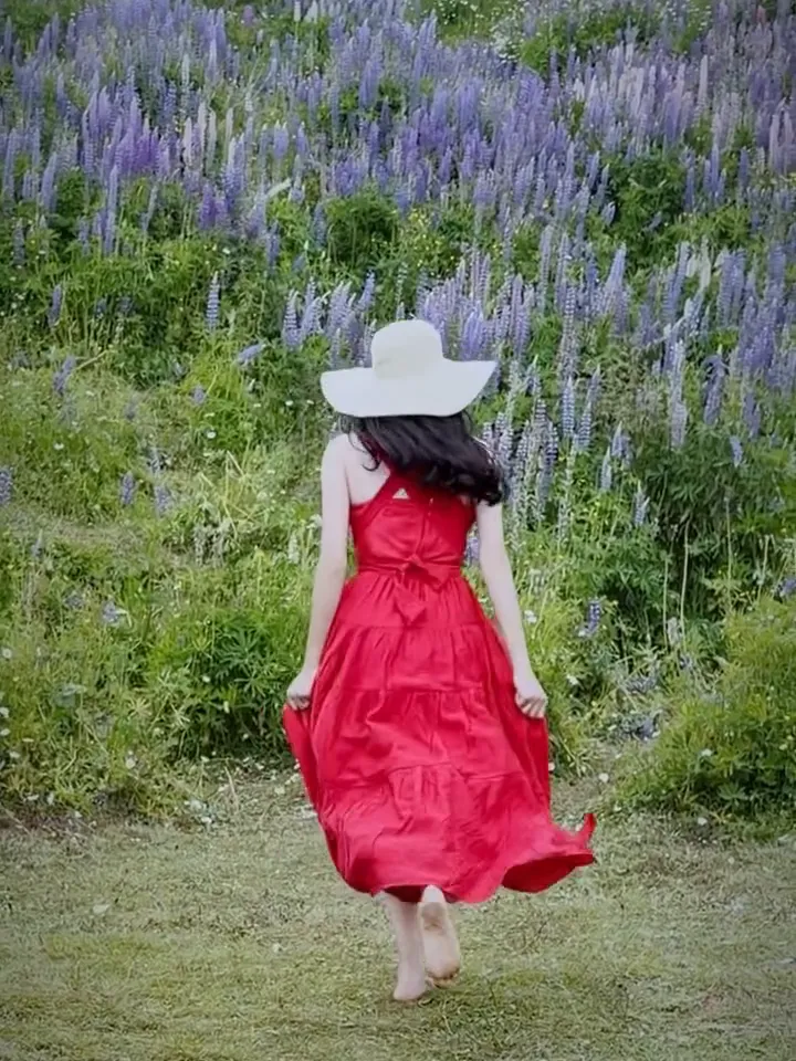 Our guest in a red dress walking across a Gulmarg clearing towards a slope of lupins