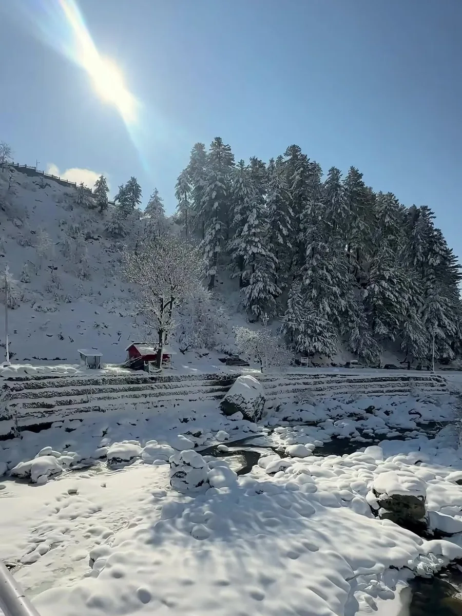 Low winter sun over snow-covered slopes and a railing in Kashmir, from our reel