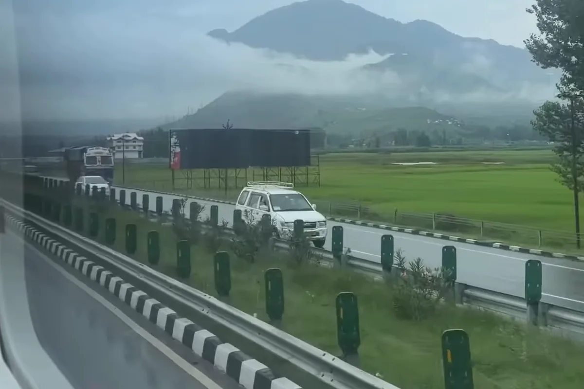 View from the bus window of misty green hills and fields beside the Jammu Srinagar highway