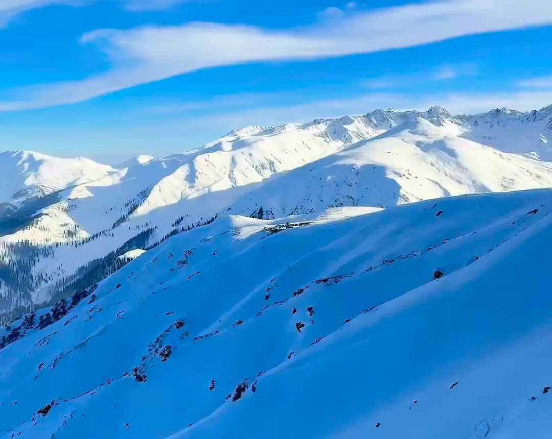 Snow-covered ridges in Kashmir under a deep blue winter sky