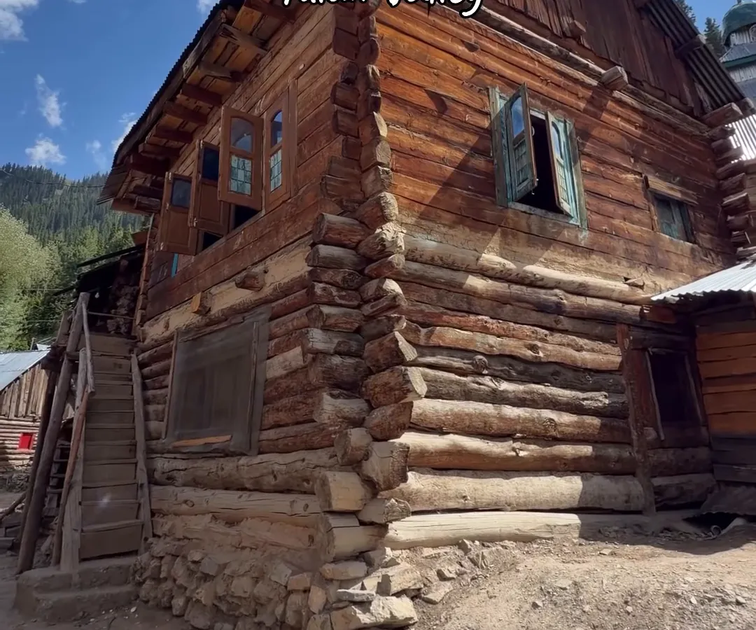 A traditional log house with a steep wooden roof in Tulail valley, Gurez, under a blue sky