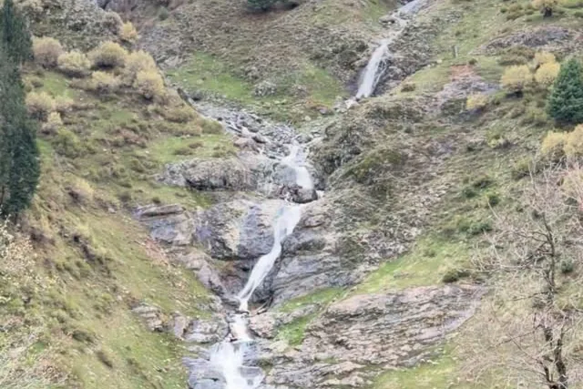 Waterfall running down a green, rocky mountainside near Pahalgam
